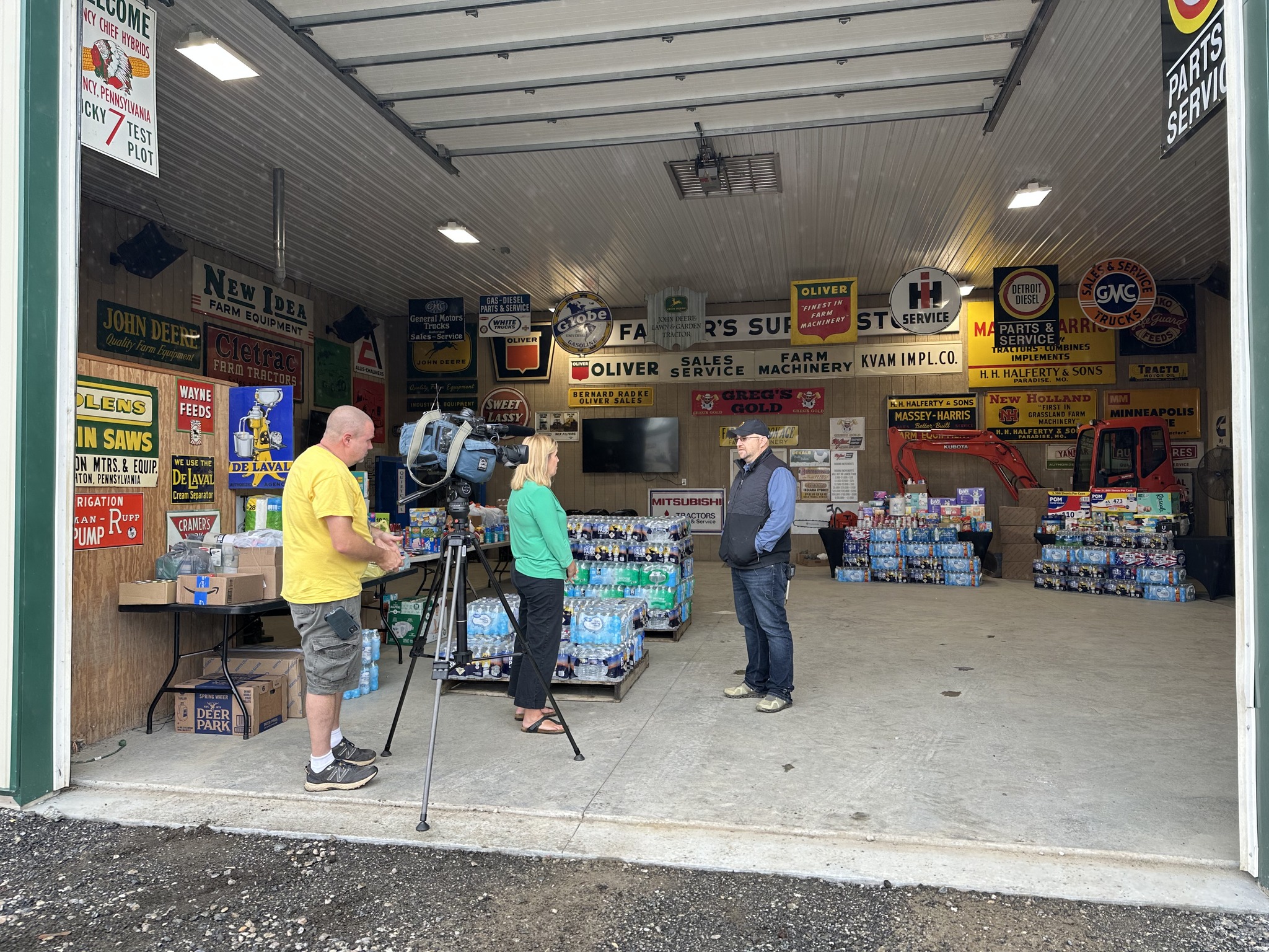 Interior of an equipment auction office or showroom with people standing and interacting near counters and displays.