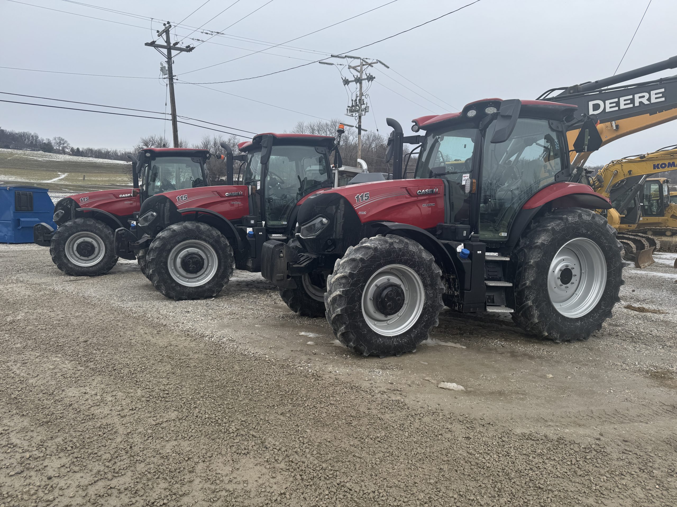 lineup of several red tractors parked on a gravel lot
