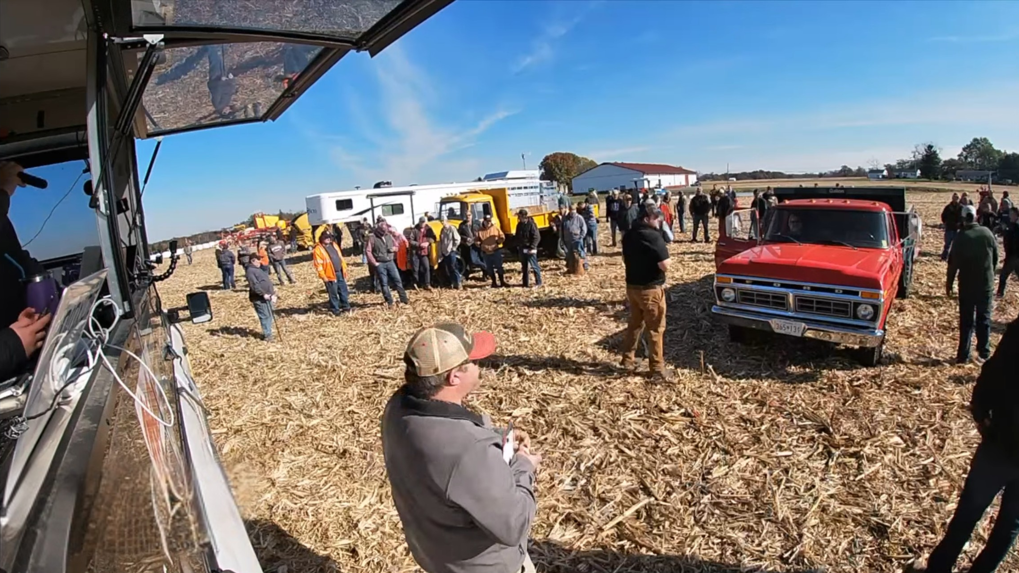 large crowd of people gathered around a red truck at an outdoor equipment auction