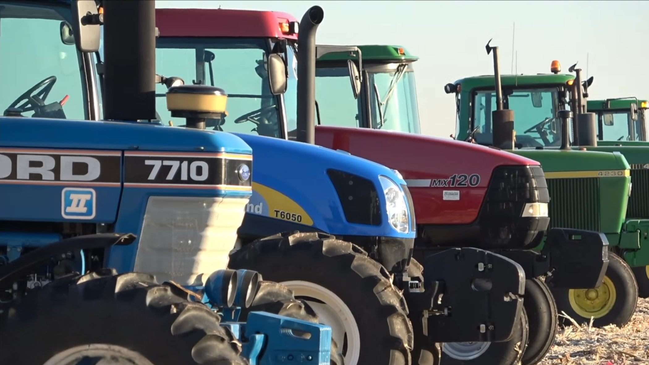 Close-up profile of a blue  tractor parked next to a red tractor