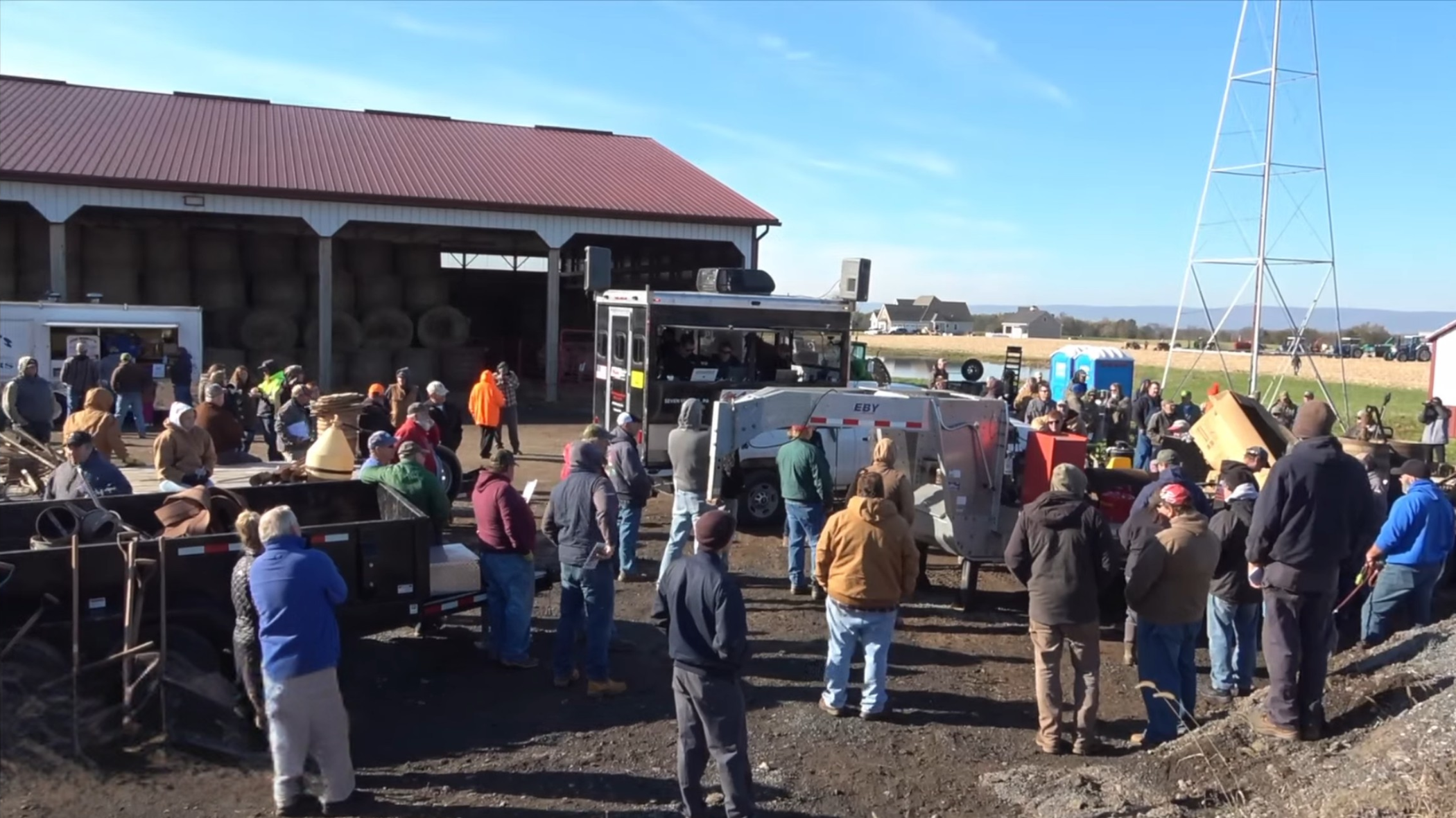 Group of people standing outside a traditional farm building at a auction event